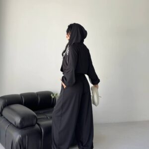 Rear view of model wearing black hooded cropped jacket and wide jogger pants, holding silver clutch, chunky sneakers. available for wholesale in Turkey.