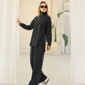 Pose de cuerpo entero con conjunto de velour negro que cuenta con top de cremallera de cuello alto, pantalón recto y zapatillas blancas.