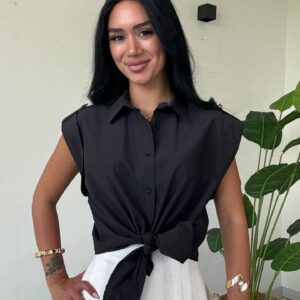 Vista de la cintura hacia arriba de blusa negra con lazo frontal combinada con una falda plisada blanca. - Mayoreo Turquía