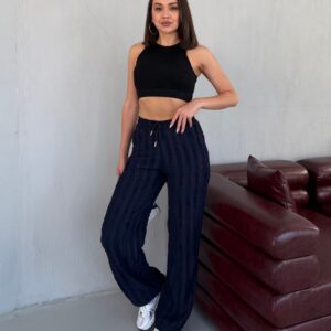 Mittellanges Porträt eines black gerippten Crop-Tops, Hand auf der Hüfte, zeigt hohen Ausschnitt und weite Armlöcher.