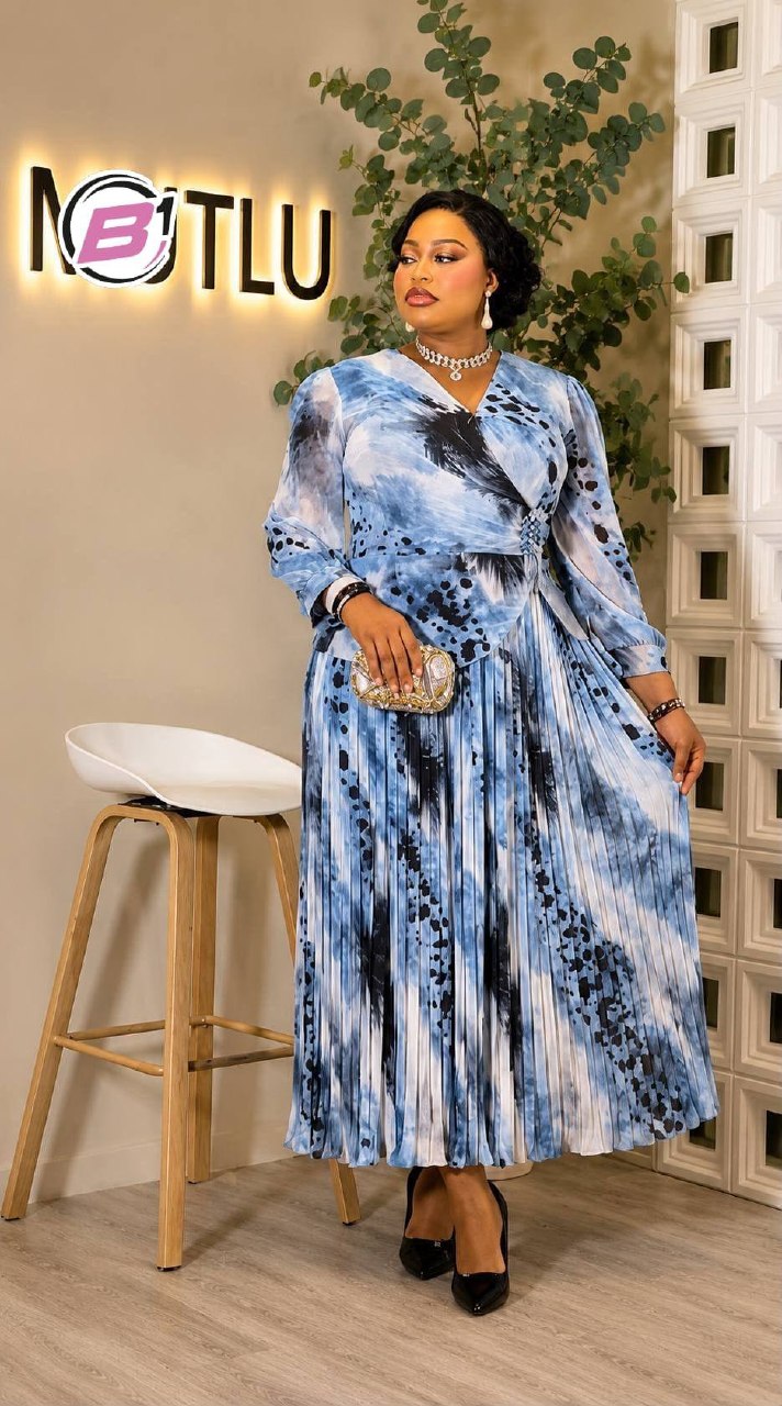 azul-plegado-envuelto-2379 – Mayorista Turquía Vista de cuerpo entero de vestido plisado azul con estampado azul acuarela, frente envolvente y mangas largas, modelo sosteniendo una pequeña cartera adornada - Mayorista Turquía.
