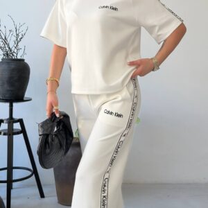 Modelo sosteniendo bolso acolchado crema junto a top burdeos y pantalones anchos a juego - Turquía Mayorista