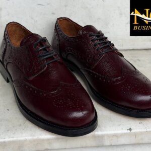 Schräg von vorne Blick auf burgunderfarbenes, geprägtes Leder-Brogue-Oxford mit dekorativen Lochungen und schwarzen Schnürsenkeln – Großhandel Türkei.