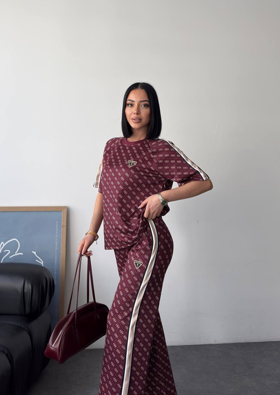 burgundy-monogram-sidebag-5601 Side view of burgundy monogram two-piece featuring cream striped piping and flared leg, model holding bag.