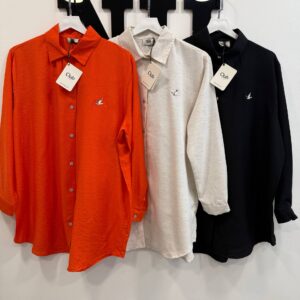 White rectangular hang tag connected by cord to an orange shirt, placed near an embroidered bird motif on the chest.