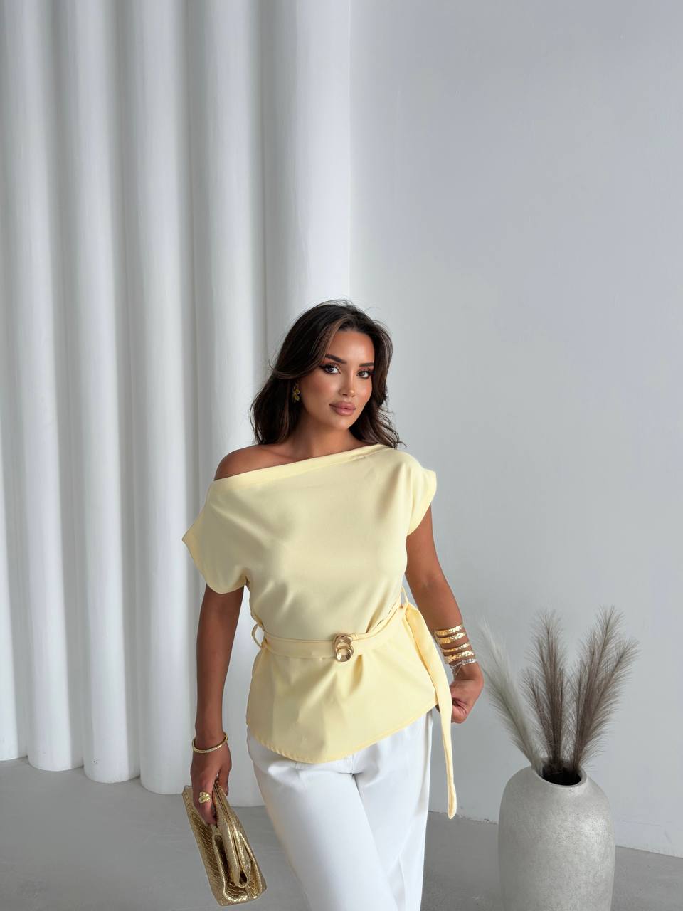 Blusa asimétrica color amarillo pálido con cinturón de aro dorado, combinada con pantalones blancos y clutch dorado. – Mayorista en Turquía Blusa asimétrica color amarillo pálido con cinturón de aro dorado, combinada con pantalones blancos y clutch dorado. - Mayorista en Turquía