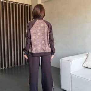 Back view of dark brown two-piece tracksuit with monogram-print back panel, piped sleeves, and wide-leg pants.