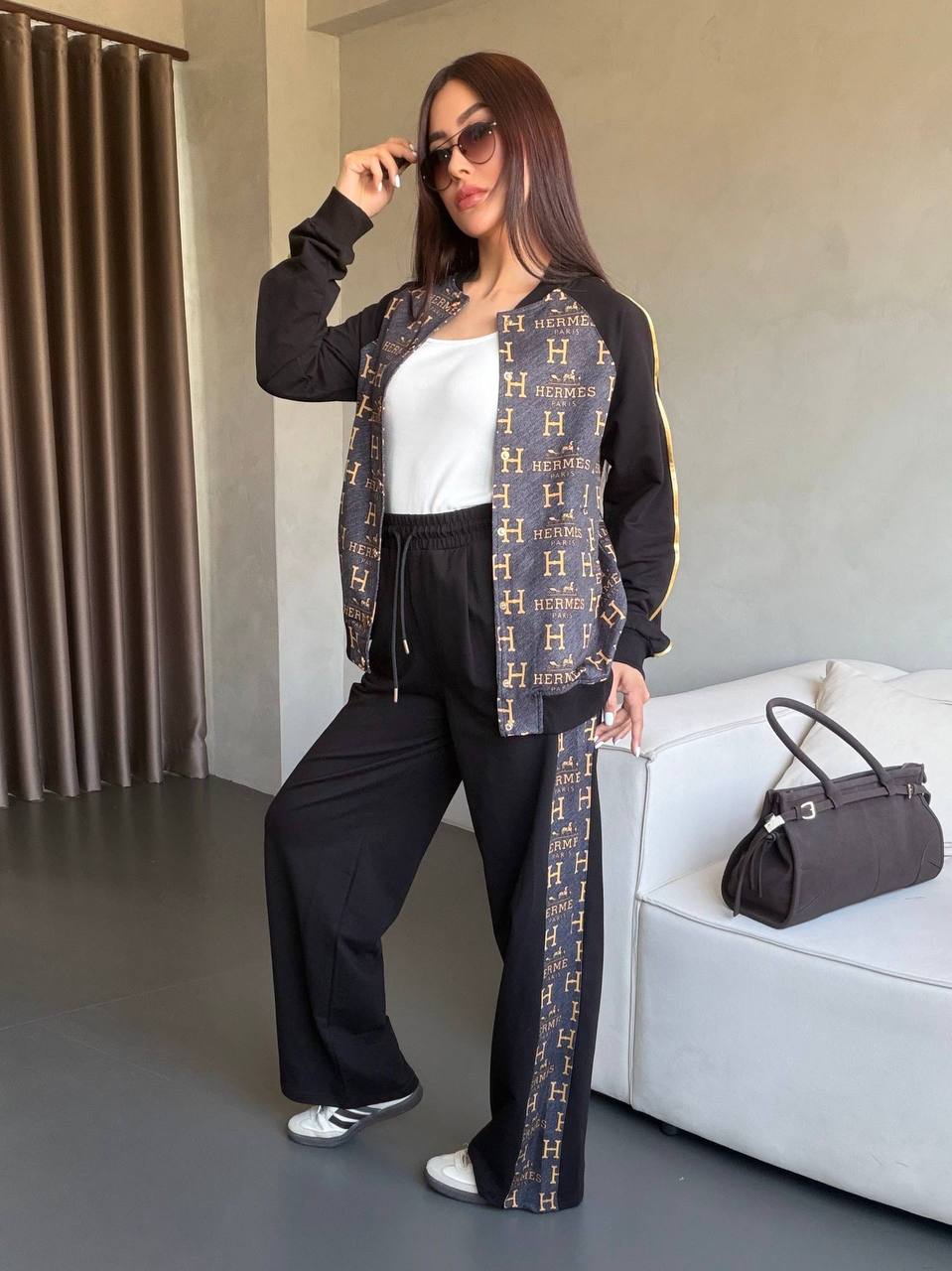 Two-piece black tracksuit with luxury brown-gold monogram panels, bomber jacket and wide-leg elastic-waist pants. Two-piece black tracksuit with luxury brown-gold monogram panels, bomber jacket and wide-leg elastic-waist pants.