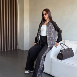 Black monogram-paneled track jacket with gold piping and matching wide-leg pants, white tank and sneakers.