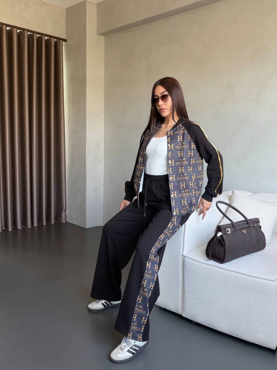 Black monogram-paneled track jacket with gold piping and matching wide-leg pants, white tank and sneakers. Black monogram-paneled track jacket with gold piping and matching wide-leg pants, white tank and sneakers.