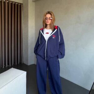 Straight-on view of navy zip jacket and wide-leg pants with white drawstring and logo-accented crop top.