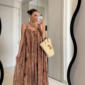Full front view of lightweight brown patterned maxi dress with adjustable tie straps and straw tote.
