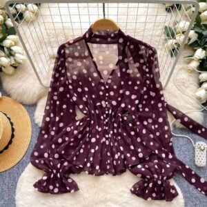 Flat lay of maroon chiffon blouse with pale pink polka dots, ruffled cuffs, button front and waist tie.