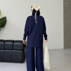Vista trasera que muestra la caída de la camisa azul marino con textura crinkle y pantalones anchos a juego, sostenidos con una tote de crochet bajo un brazo - Turquía al por mayor.