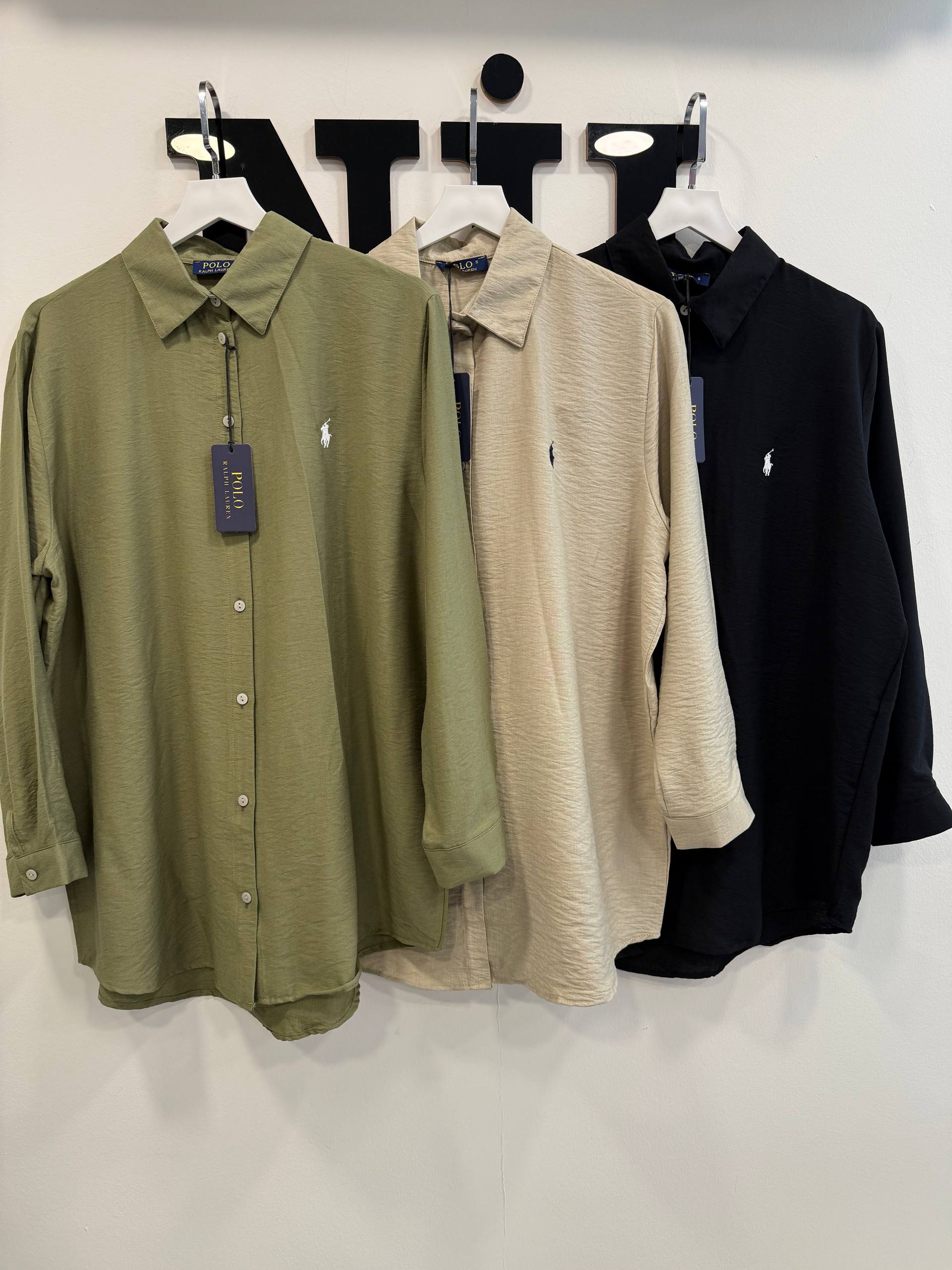 olive-beige-black-row-7391 Row of three textured shirts in olive, cream and black with visible collars, buttons and small stitched logos on the chest.