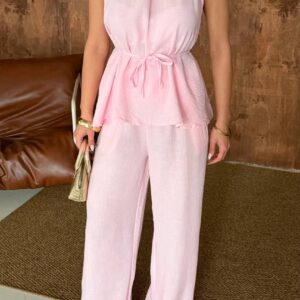 Front view pastel pink halter top with peplum tiers and tied waist over flowing wide-leg trousers.