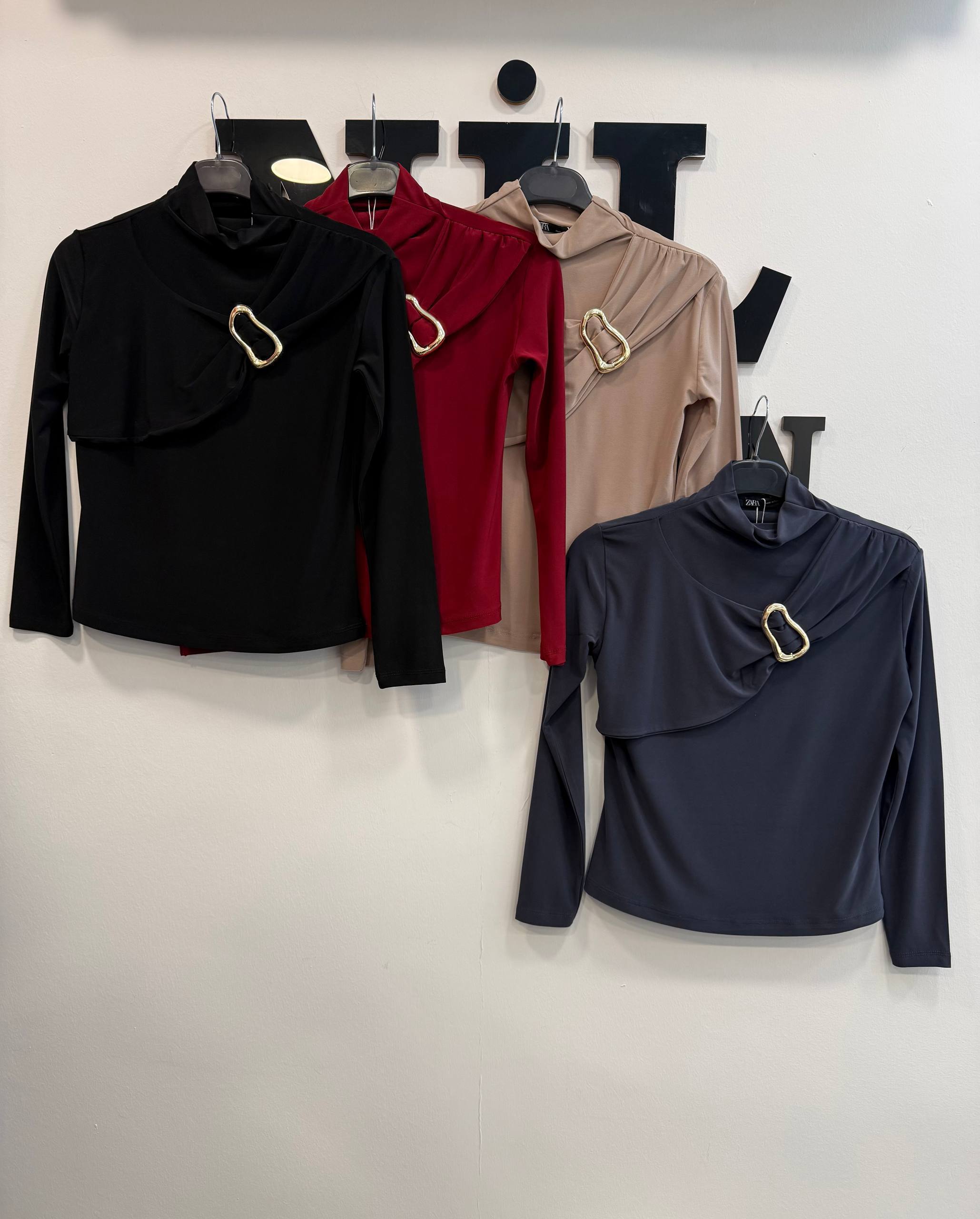 tops-hem-view-5623 Hanging view of three draped tops showing hems and long sleeves in olive, white and navy with soft gathered shoulders.
