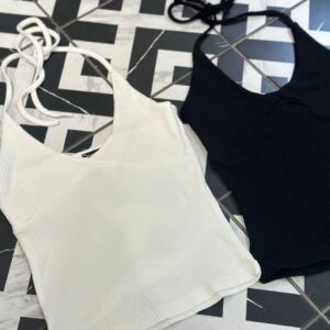 Disposición plana de dos tops halter canalé en blanco y negro sobre un suelo geométrico, mostrando textura y tirantes - Mayorista Turquía.