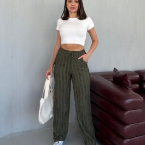 Model trägt ein white kurzes Crop-Top mit hohem Bund, drawstring texturierten maroon Hosen, und Hand ruht auf der Hüfte.