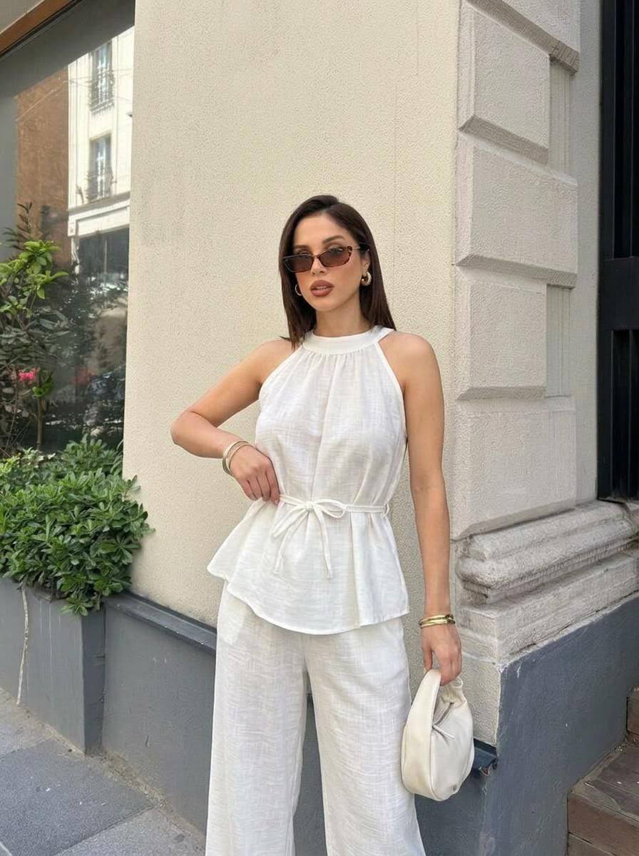 white-peplum-street-7412 Street portrait of white textured halter peplum top with waist tie and loose wide-leg pants, accessorized with small white handbag.