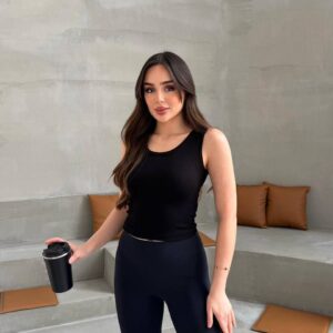 Front view of black cropped ribbed tank top paired with high-waist black leggings, model holding a black travel mug. available for wholesale in Turkey.