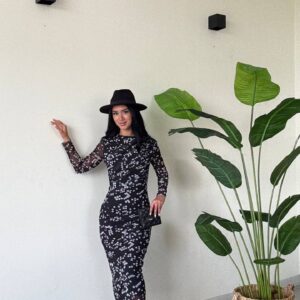 Full-length image of black dotted midi dress paired with a wide-brim hat, clutch and pointed heels.