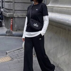Foto de cuerpo entero de modelo con camiseta en capas negra sobre mangas largas blancas, pantalones anchos y bolso cinturón cruzado. Disponible para venta mayorista en Turquía - Mayorista en Turquía