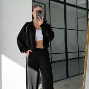 Spiegel-Selfie einer schwarzen Zip-Jacke und einer Hose mit weitem Bein, weißem Seitenstreifen und elastischem Bund.