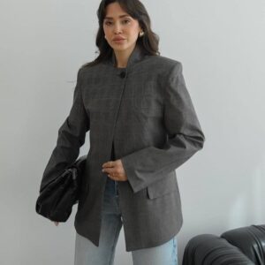 Close-up of blazer front showing stand collar, top button, subtle check pattern and structured shoulders.