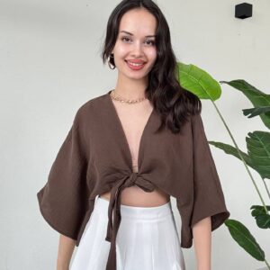 Front view of deep brown tie-front blouse featuring oversized sleeves and paired with a high-waist white pleated skirt.