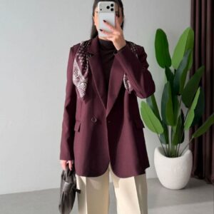 Straight-on view of burgundy tailored blazer with patterned neck scarf, flap pockets, and cream wide-leg trousers.