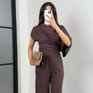 Schokoladenbraunes asymmetrisches Draped-Top mit geraffter Taille und weiten Hosen; Model hält eine mit Nieten bestückte Clutch. Türkei-Großhandel.