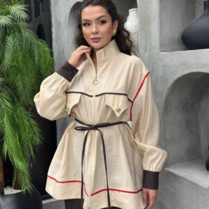 Dreiviertelansicht der beigen Jacke mit hochstehendem Kragen, Puffärmel und dunklen Kontrastbündchen mit Knopfdetails - Türkei Großhandel.