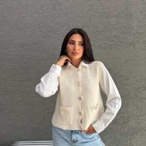 Modell trägt cremefarbene, ärmellose Strickweste mit markanter Knopfleiste und zwei vorderen Patch-Taschen.