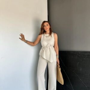 Vorderansicht eines Models in cremefarbenem ärmellosen Top und passenden weiten Hose mit seitlicher Bindung und asymmetrischem Saum. - turkei-grosshandel