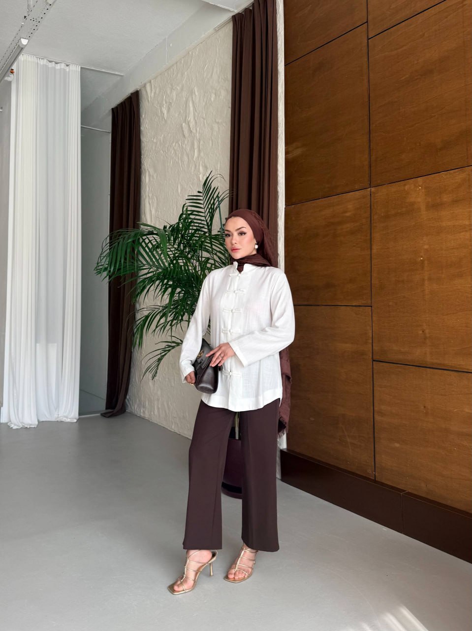full-length-outfit-3472 Full-length shot of model wearing a white mandarin-collar tunic, brown wide-leg trousers, brown hijab and strappy gold heels.