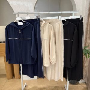 Exhibidor de ropa con chaquetas con capucha en azul marino, crema y negro y pantalones de pierna ancha con ribetes en contraste.