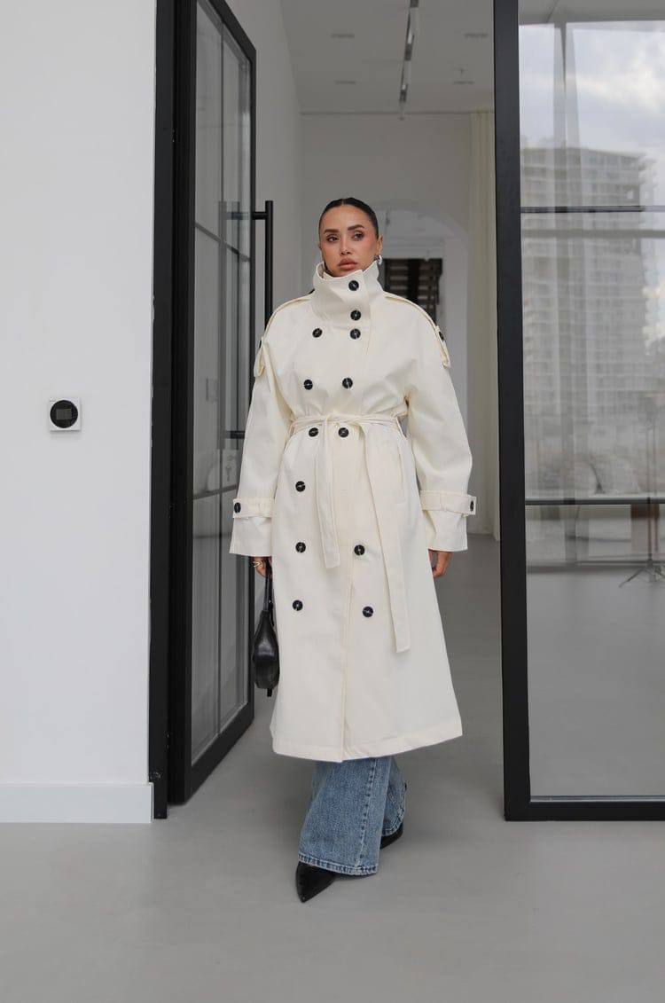 elfenbein-trench-hoher-kragen-7423-Großhandel-Tuerkei Vorderansicht eines elfenbeinfarbenen Trenchcoats mit doppelreihigem Vorderteil, hohem Kragen, schwarzen Knöpfen, Gürtel und kleiner schwarzer Tasche. Großhandel Türkei verfügbar.