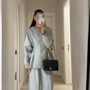 Mirror selfie showing pale grey loose two-piece with gold buttons and black quilted chain-strap handbag.