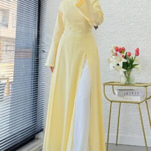 Selfie de espejo de modelo con vestido maxi en A-line de color amarillo palido, mangas largas, costuras discretas y forro blanco visible. - Mayorista Turquía