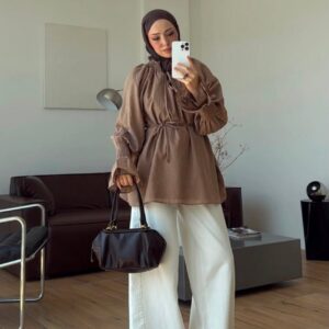 Modelo con tunica color moka relajada, puños fruncidos y cinturón para atar, combinada con pantalones blancos de pierna ancha, sandalias y bolso negro. - Mayorista en Turquia