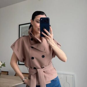 Mirror selfie close-up of mocha double-breasted trench top with wide cuffed sleeves, tied waist belt and matte black buttons.