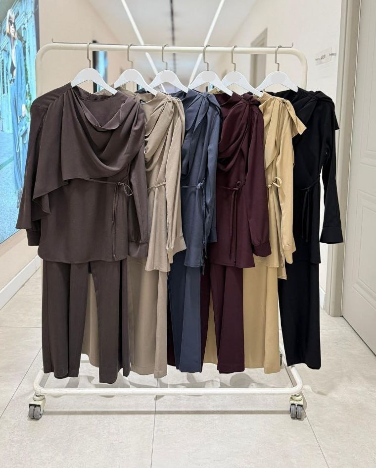 multi-color-rack-2267 Clothing rack displaying draped tunics and wide trousers in multiple colors including beige, navy and burgundy.