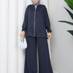 Vista frontal de conjunto de punto azul marino con cremallera central dorada, chaqueta con paneles y pantalones anchos y fluidos, con hiyab gris claro. - Mayorista Turquía