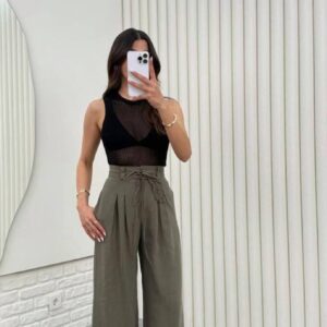 Vista frontal de pantalones anchos de cintura alta color oliva con pliegues frontales y cordón, estilizados con top sin mangas negro. - Mayorista en Turquía.