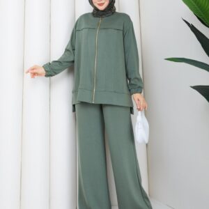 Front view of olive zip jacket with vertical seams and matching wide trousers, styled with dark patterned hijab and white bag.