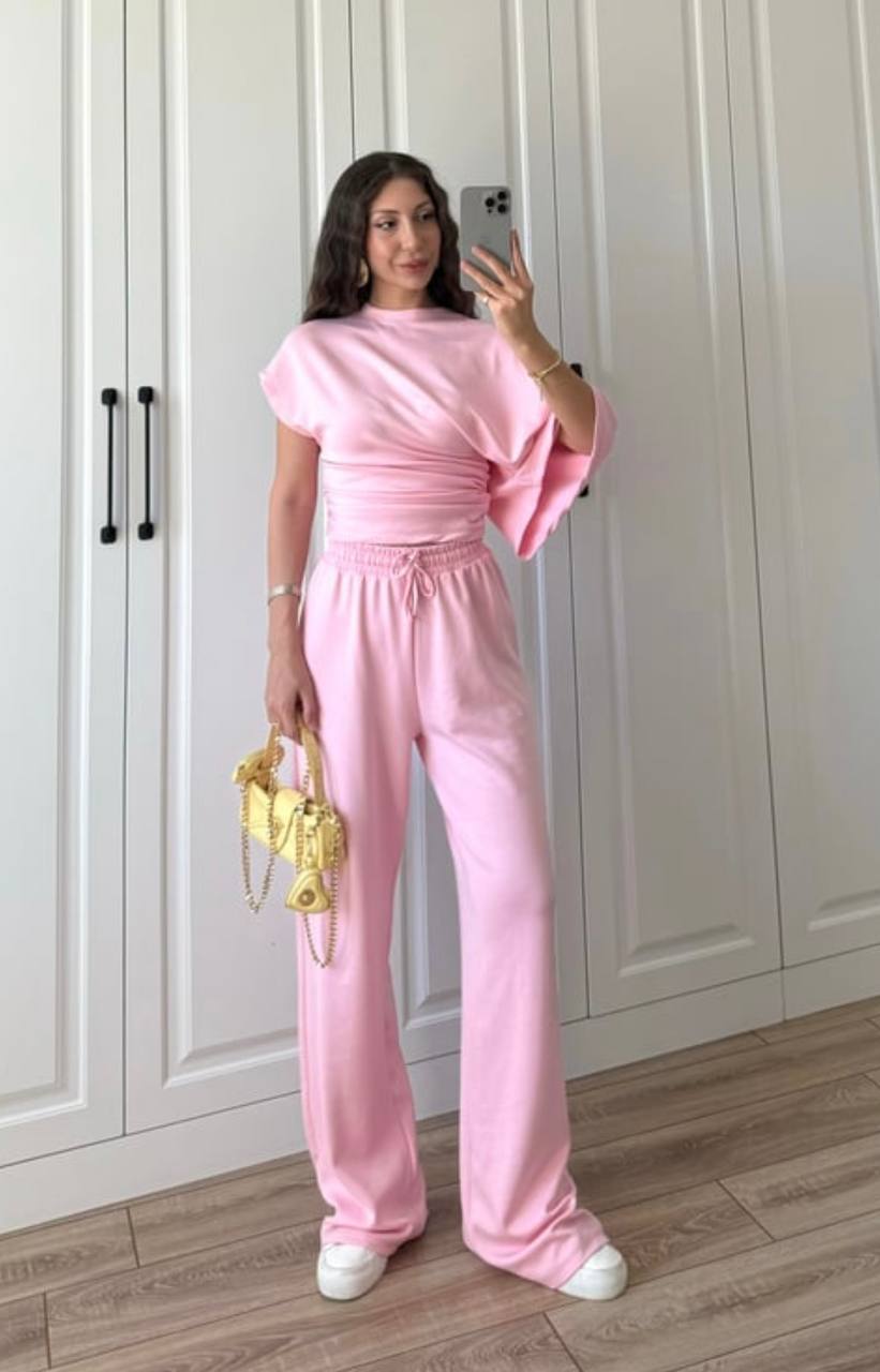 Rosa lockeres Loungewear-Set 5910 – Türkei Großhandel Model in zartem Rosa mit asymmetrischem Draped-Top und elastischem Bund der weit fallenden Hose, stilvoll mit einer kleinen goldenen Handtasche. Türkei-Großhandel.