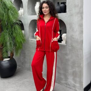 Chaqueta roja con cremallera, bolsillos frontales y dobladillo fruncido, combinada con pantalones rojos de pierna ancha y raya lateral crema.