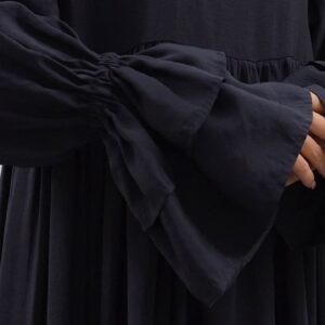 Close detail of flared layered cuff with smocked sleeve seam and matte black fabric texture.