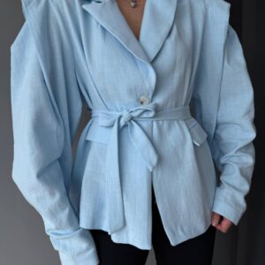 Close-up of sky blue textured blazer showing waist tie, single button, and puffed sleeves